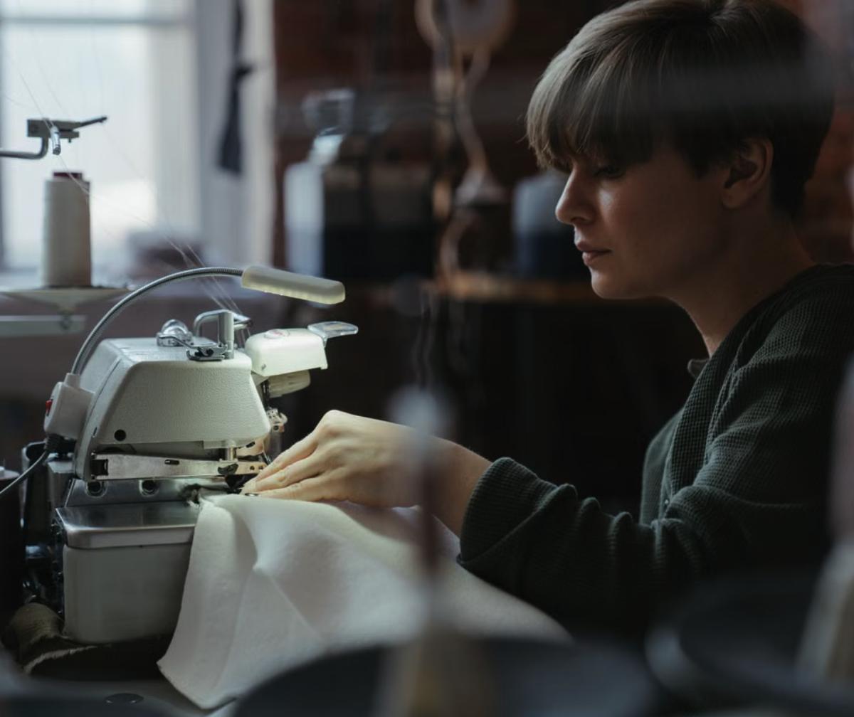 Operaria trabajando con una maquina overlock industrial en un taller de confeccion