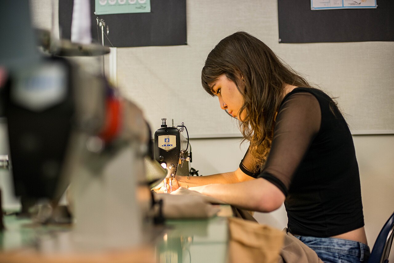 Alumna de una escuela de moda cosiendo con una máquina de coser industrial